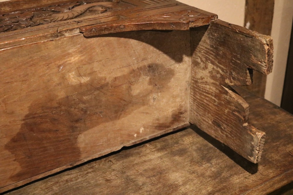 A dark brown carved oak chest featuring relief carvings of dragons, floral rosettes, and a central iron lock plate. View XVII