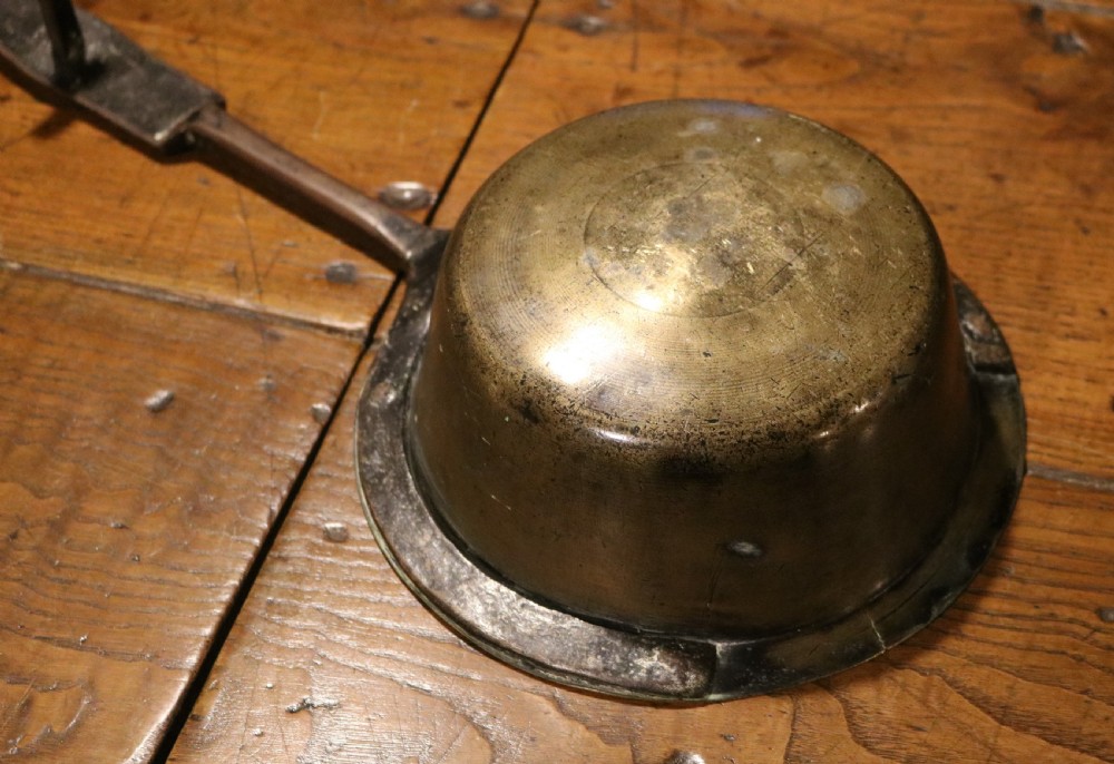 A Georgian brass hearth skillet featuring a rounded brass bowl joined to a long wrought iron handle with an integrated support rest. View II