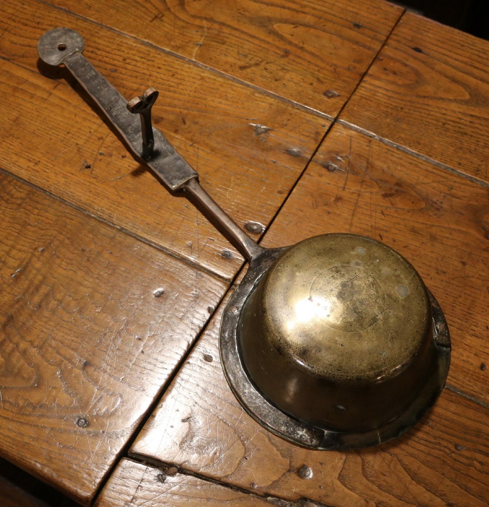 A Georgian brass hearth skillet featuring a rounded brass bowl joined to a long wrought iron handle with an integrated support rest. View IV