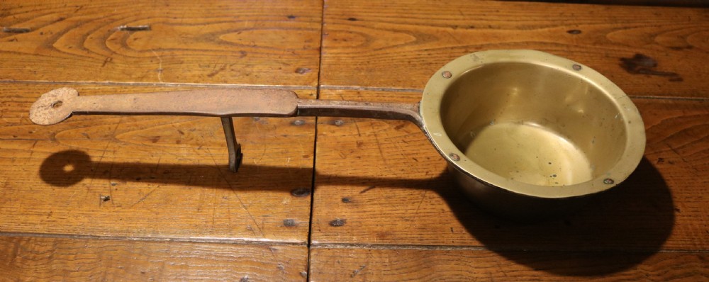 A Georgian brass hearth skillet featuring a rounded brass bowl joined to a long wrought iron handle with an integrated support rest. View V