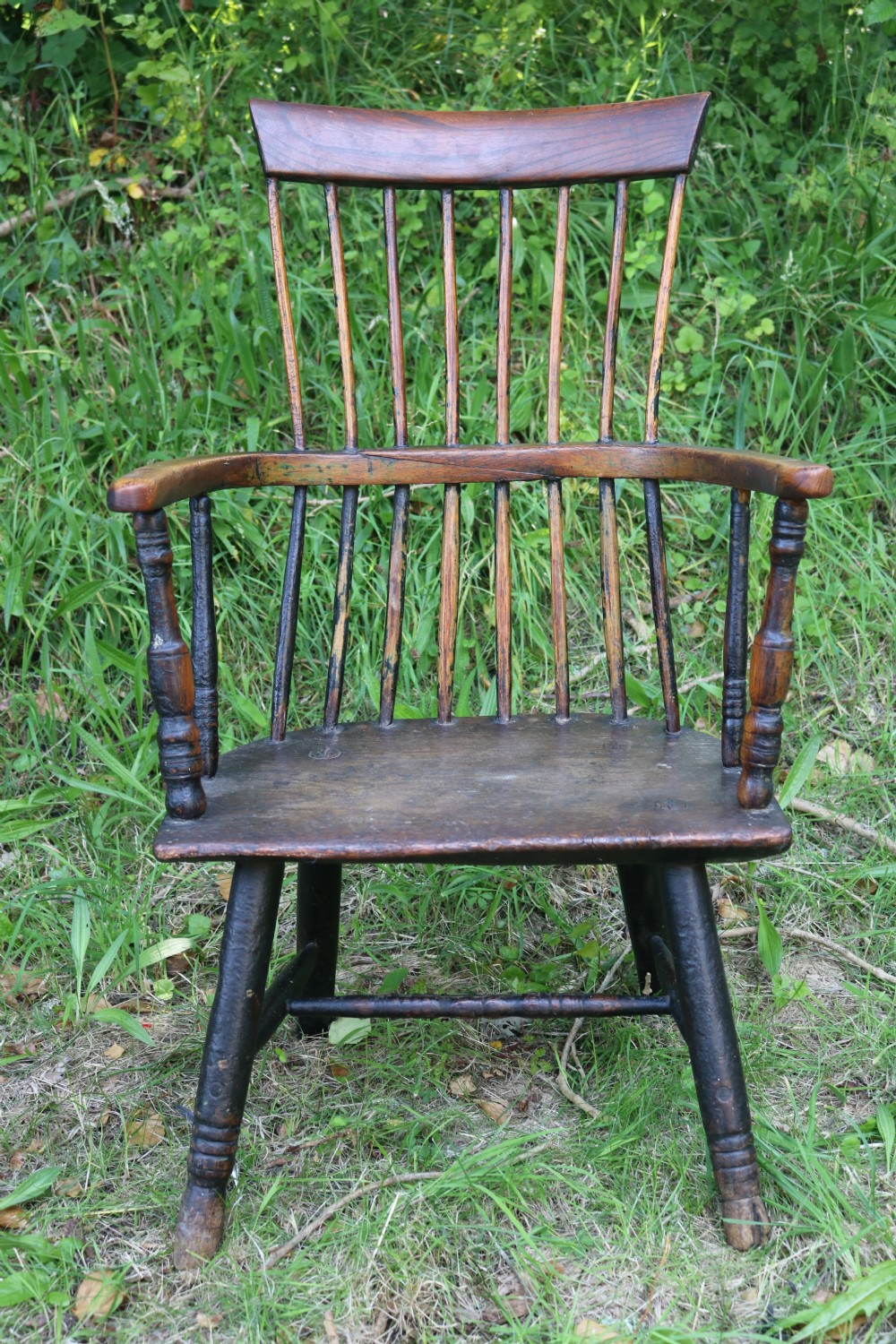 An eighteenth-century Welsh stick chair crafted from dark patinated wood featuring a comb back, curved armrests, and splayed turned legs. View II