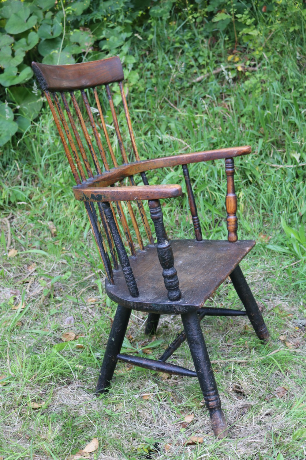 An eighteenth-century Welsh stick chair crafted from dark patinated wood featuring a comb back, curved armrests, and splayed turned legs. View III