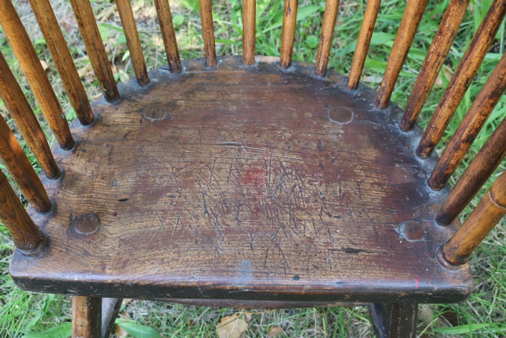 An 18th-century dark oak Welsh stick armchair featuring a shaped comb back, spindle uprights, a solid slab seat, and splayed legs. View VII