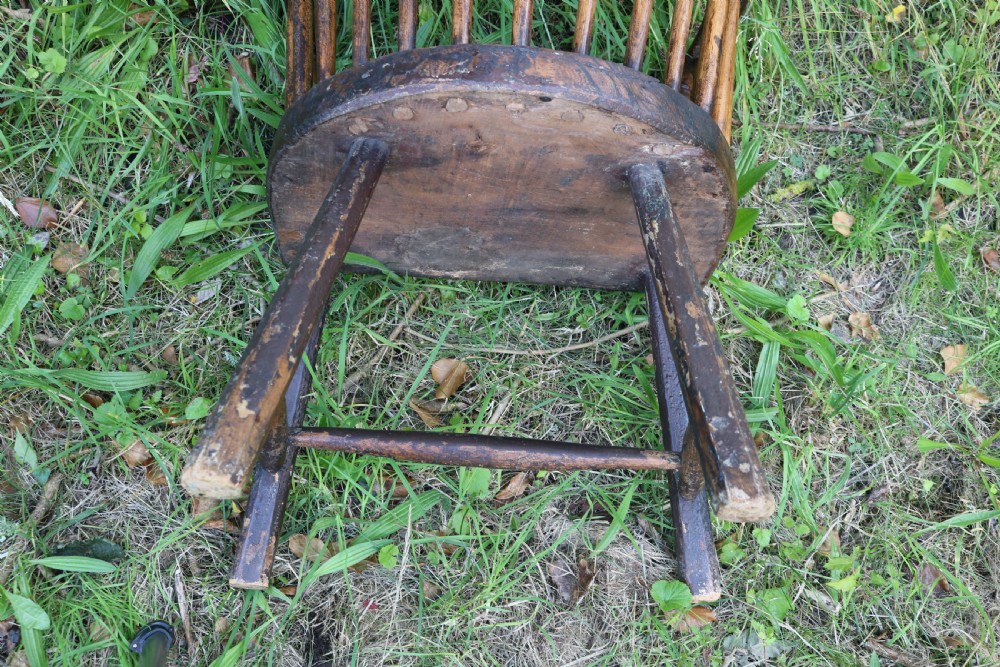 An 18th-century dark oak Welsh stick armchair featuring a shaped comb back, spindle uprights, a solid slab seat, and splayed legs. View VIII