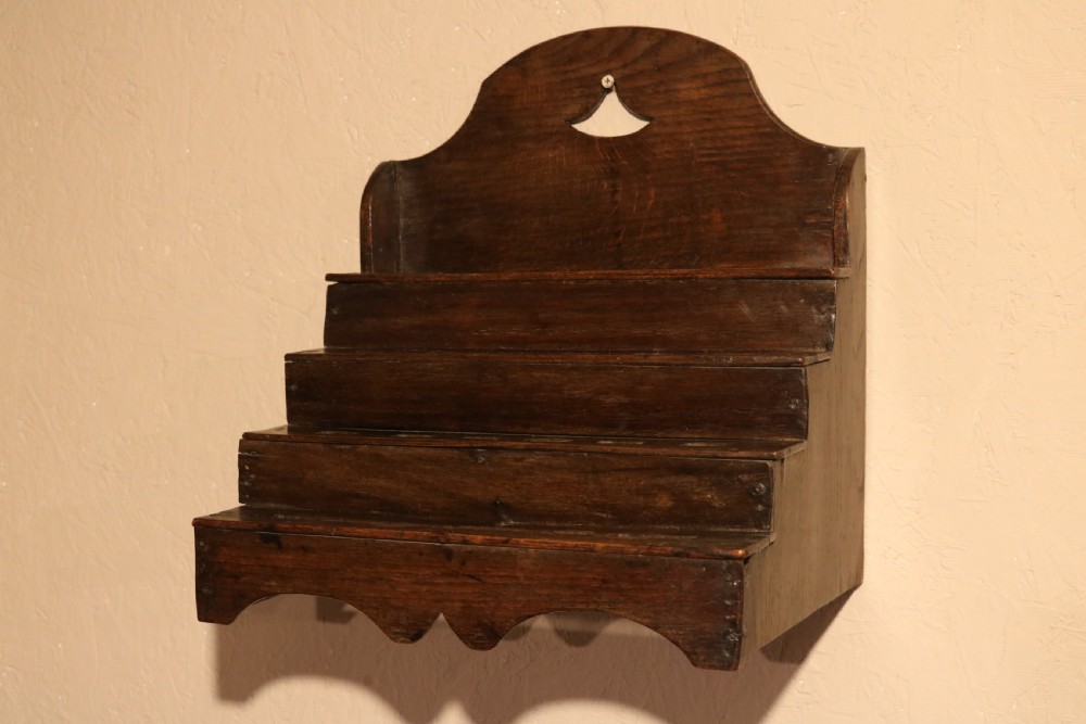 An 18th-century tiered dark oak spoon rack featuring a shaped cresting with a pierced cutout and multiple slotted shelves. View II
