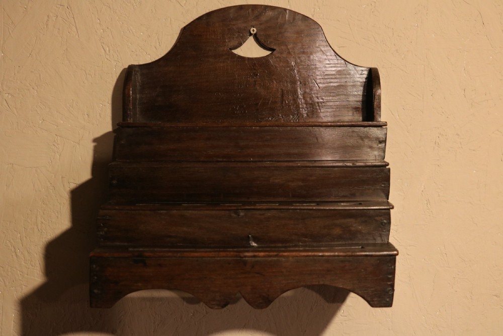 An 18th-century tiered dark oak spoon rack featuring a shaped cresting with a pierced cutout and multiple slotted shelves. View III