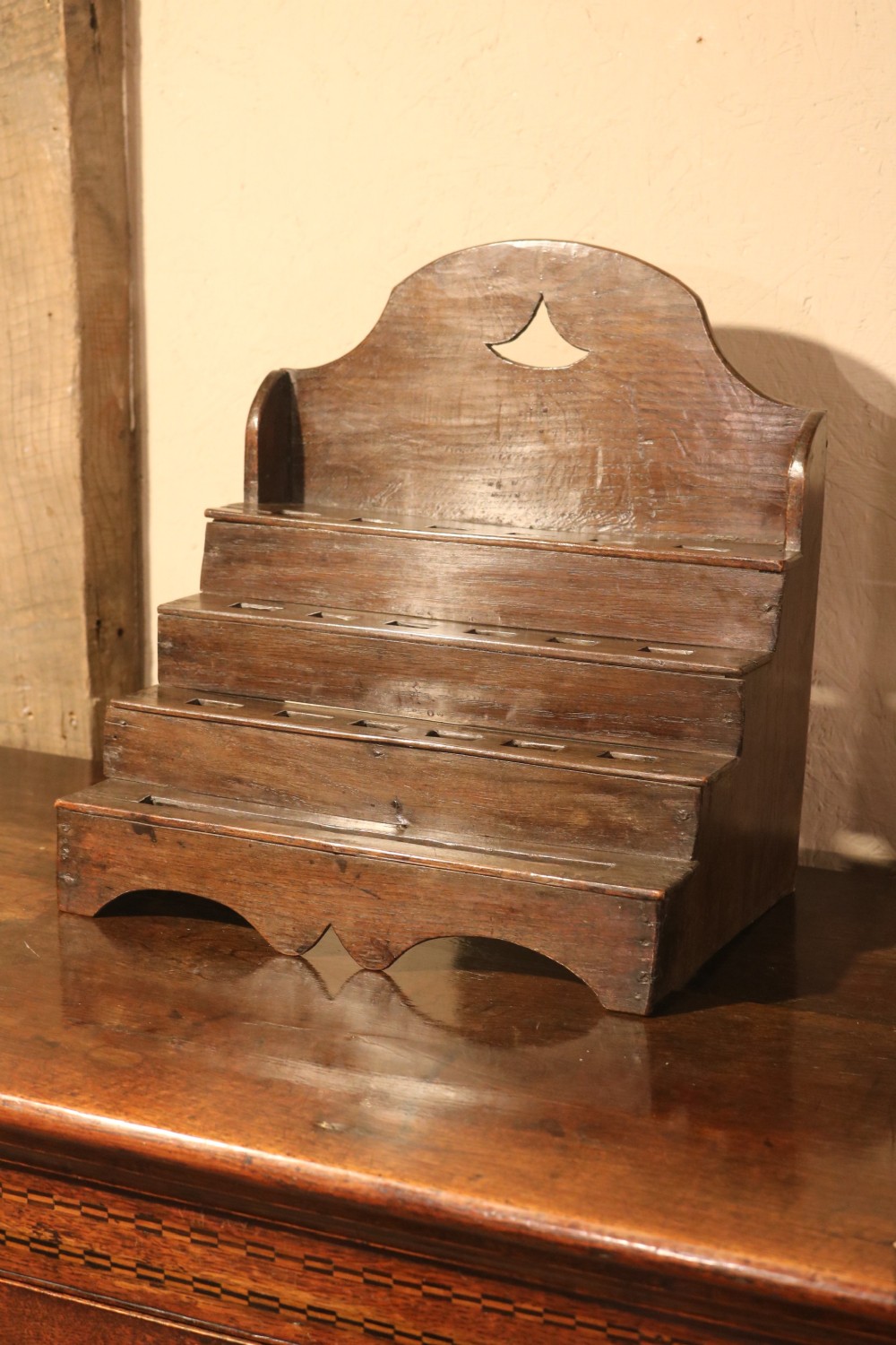 An 18th-century tiered dark oak spoon rack featuring a shaped cresting with a pierced cutout and multiple slotted shelves. View V