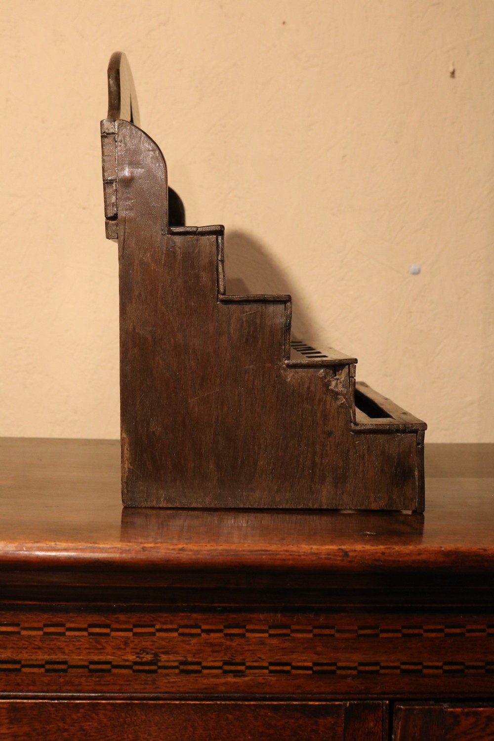 An 18th-century tiered dark oak spoon rack featuring a shaped cresting with a pierced cutout and multiple slotted shelves. View VI