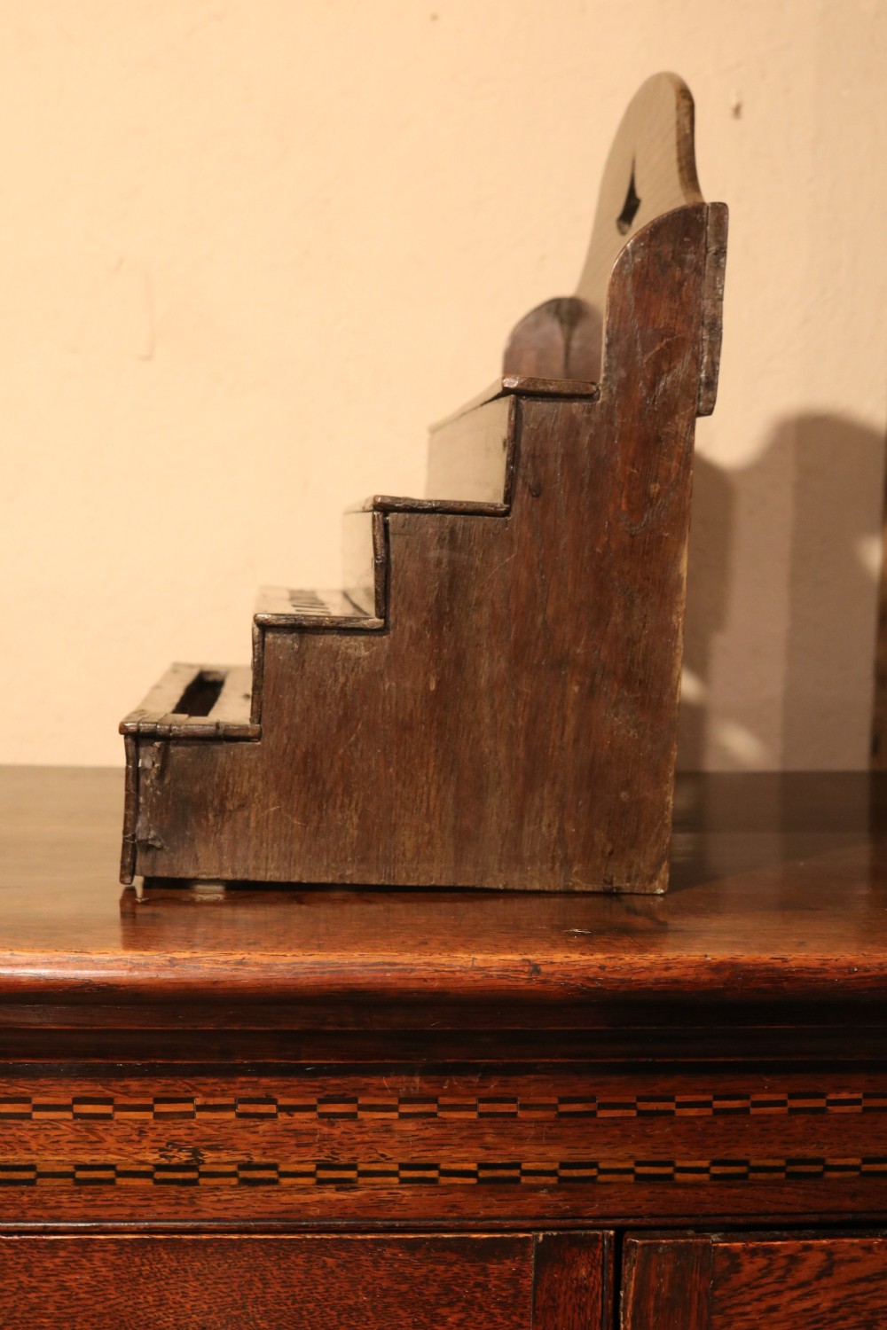 An 18th-century tiered dark oak spoon rack featuring a shaped cresting with a pierced cutout and multiple slotted shelves. View VII