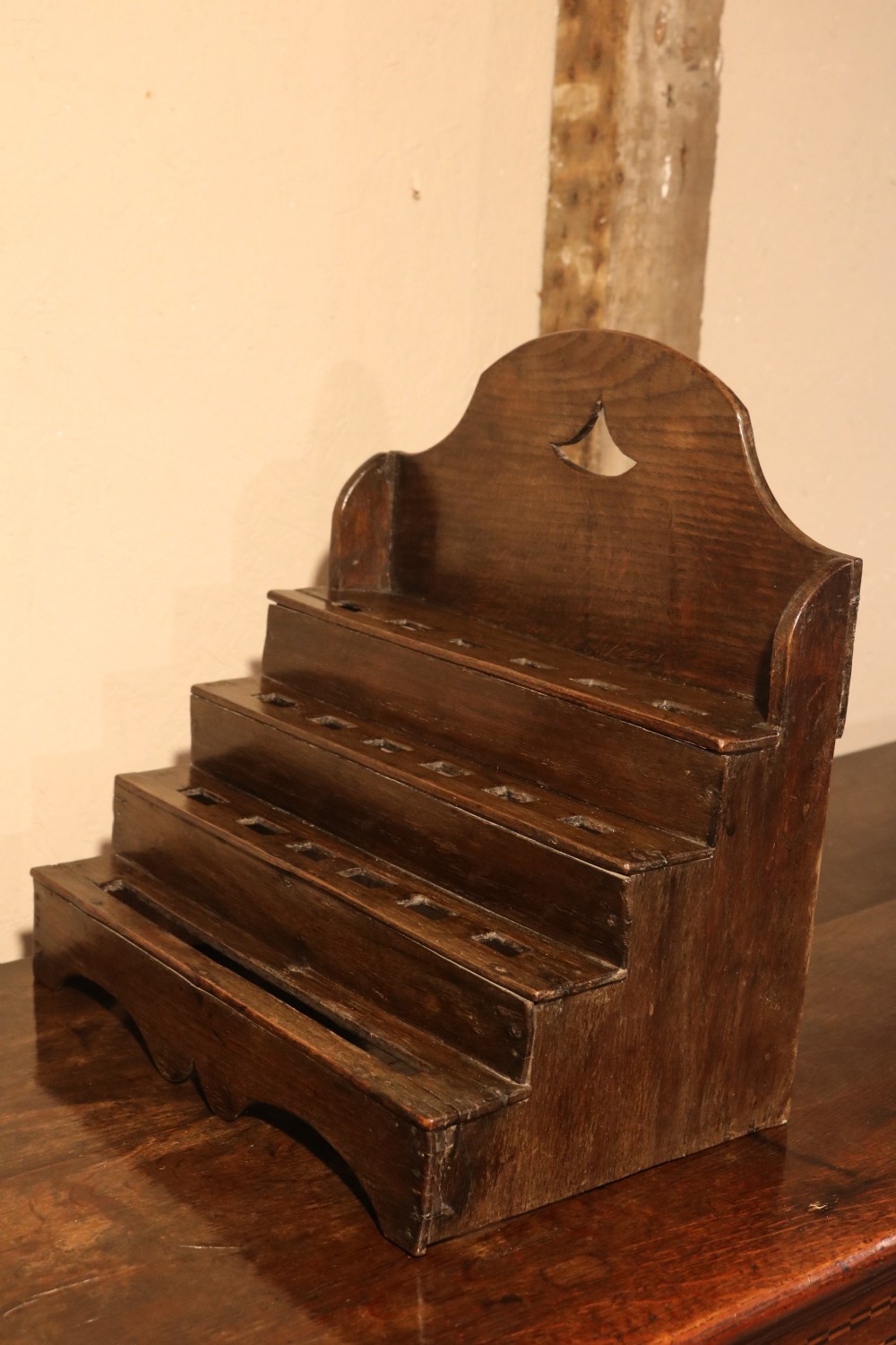 An 18th-century tiered dark oak spoon rack featuring a shaped cresting with a pierced cutout and multiple slotted shelves. View IX