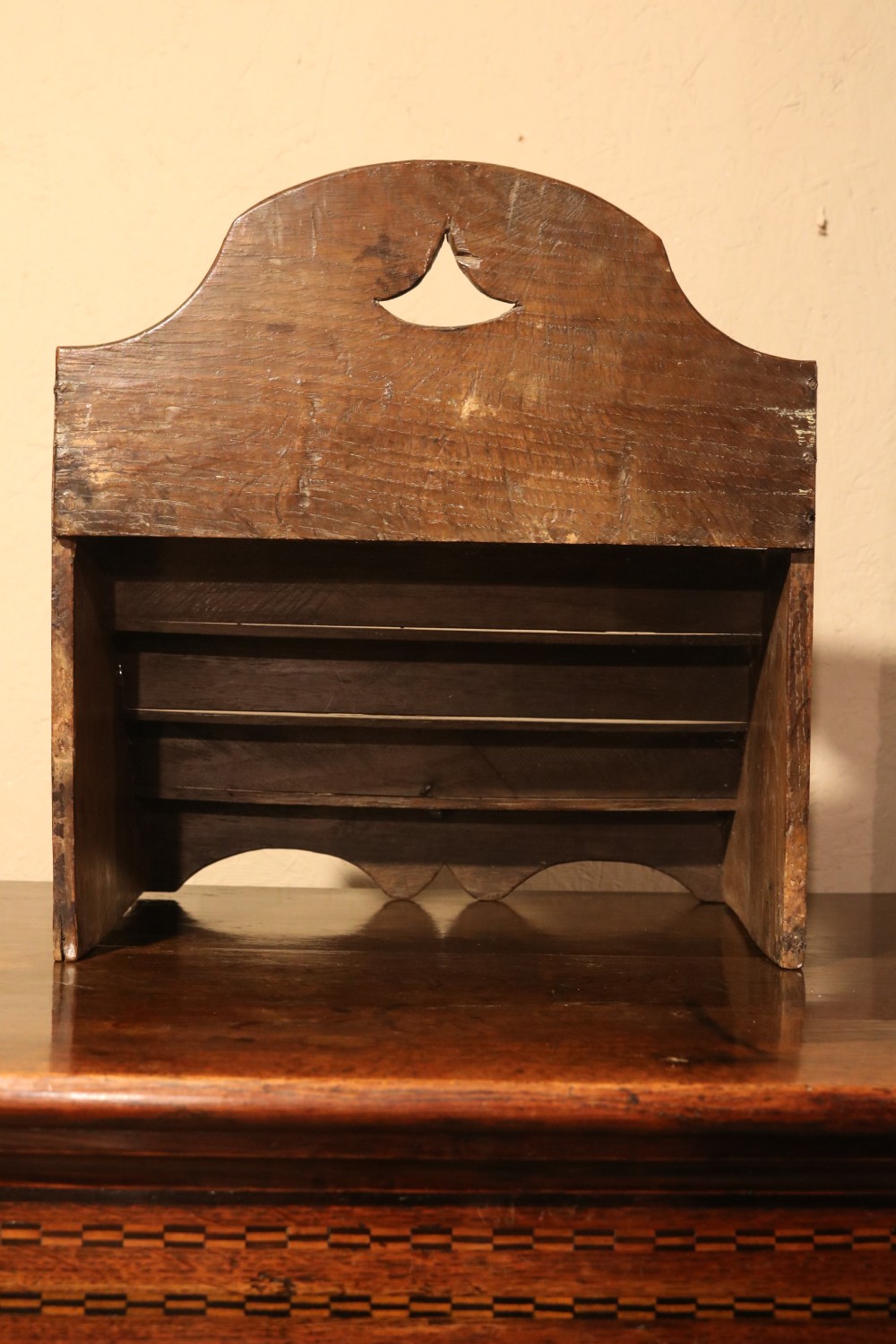 An 18th-century tiered dark oak spoon rack featuring a shaped cresting with a pierced cutout and multiple slotted shelves. View X