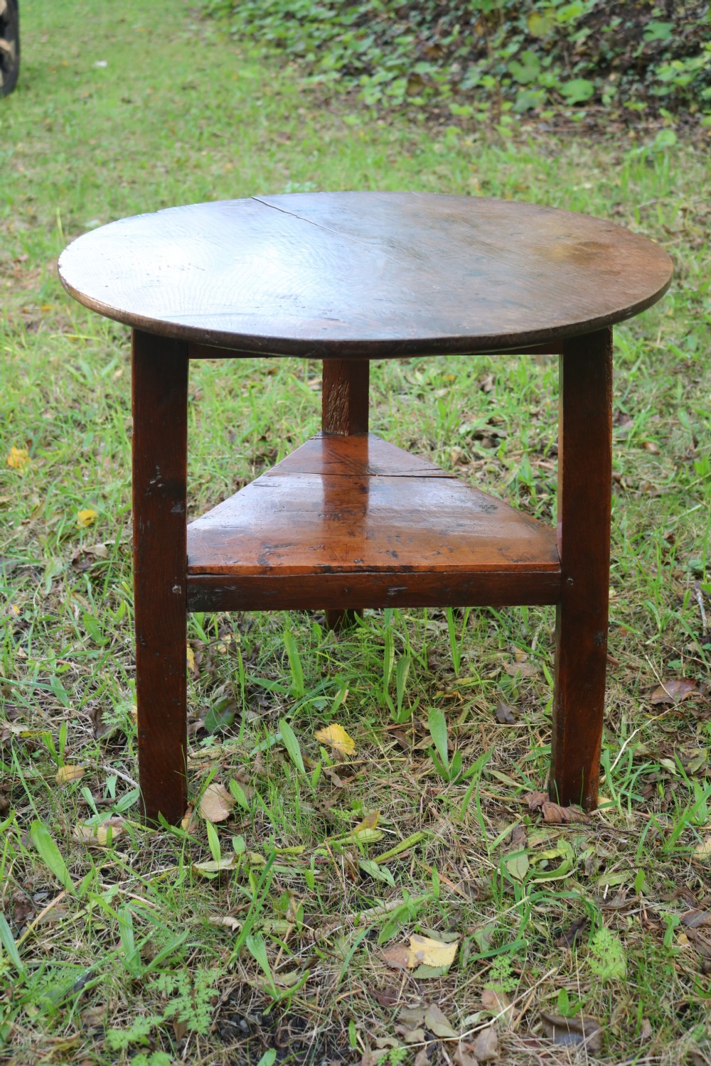A Georgian three-legged oak cricket table featuring a circular top and a lower triangular stretcher shelf. View X