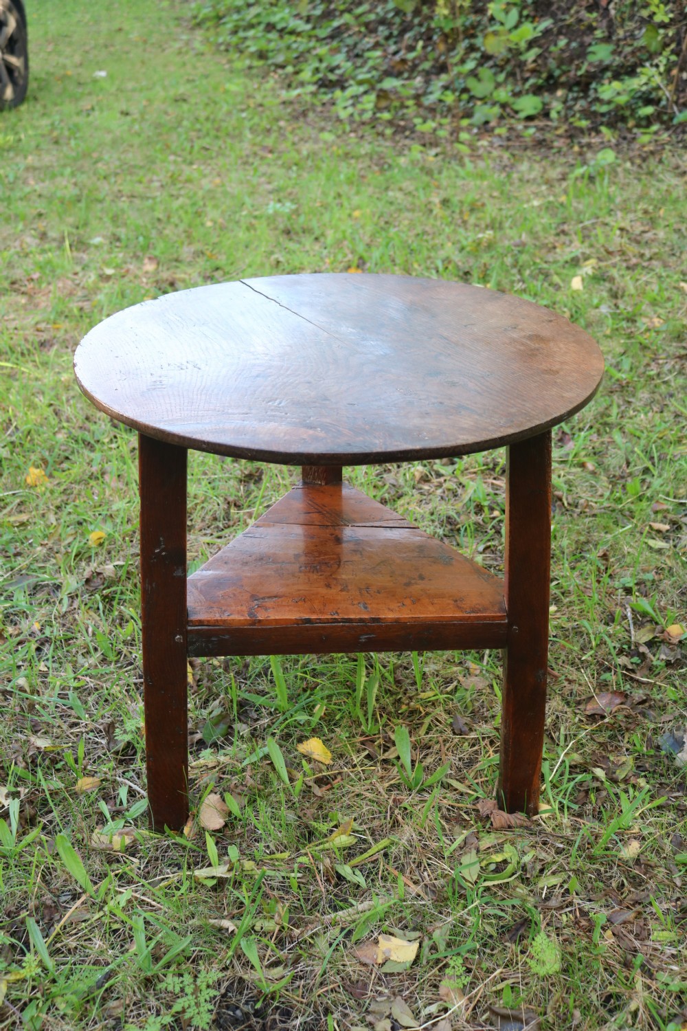A Georgian three-legged oak cricket table featuring a circular top and a lower triangular stretcher shelf. View XI