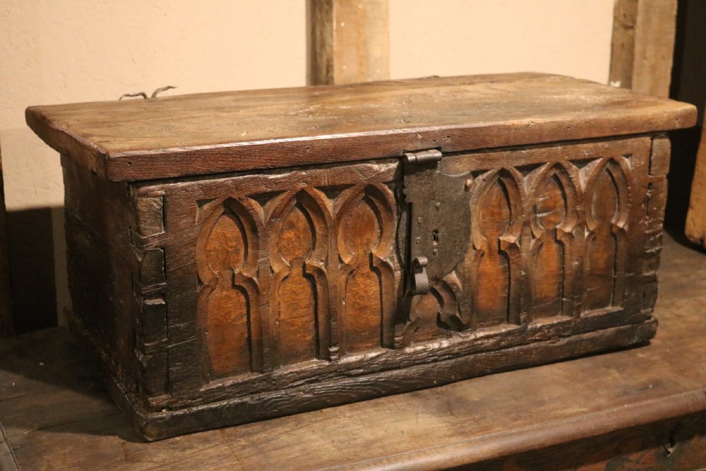 An antique dark brown chestnut wood deed box featuring carved Gothic arch panels and a hand-forged iron lock plate on the front. View II