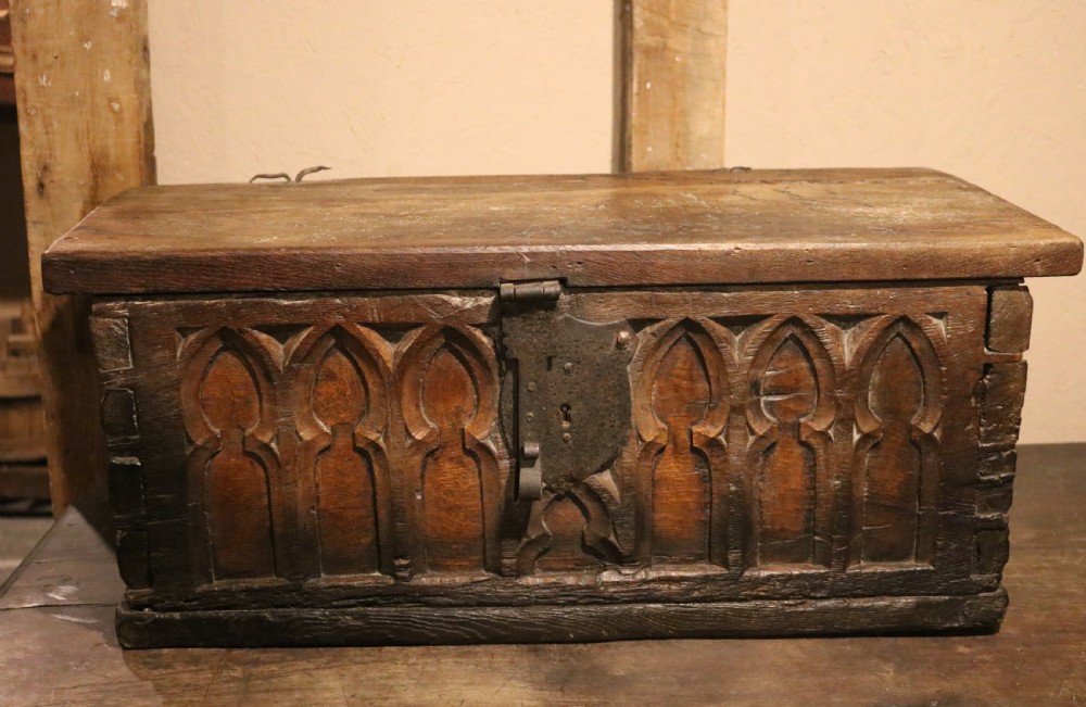 An antique dark brown chestnut wood deed box featuring carved Gothic arch panels and a hand-forged iron lock plate on the front. View III