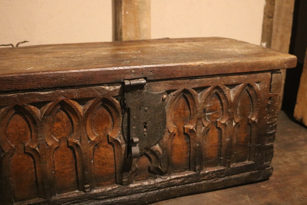 An antique dark brown chestnut wood deed box featuring carved Gothic arch panels and a hand-forged iron lock plate on the front. View VII