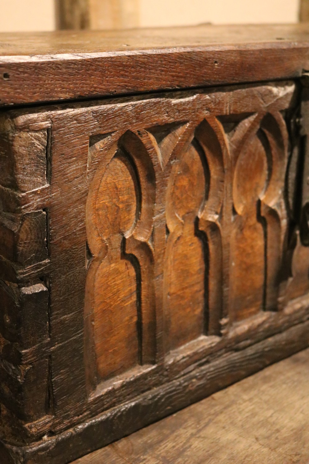 An antique dark brown chestnut wood deed box featuring carved Gothic arch panels and a hand-forged iron lock plate on the front. View VIII