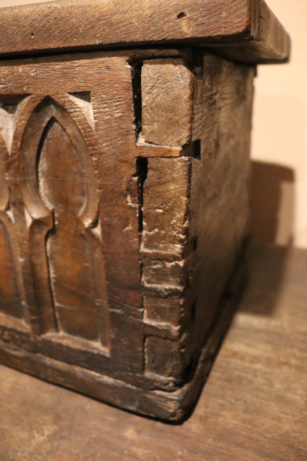 An antique dark brown chestnut wood deed box featuring carved Gothic arch panels and a hand-forged iron lock plate on the front. View XV