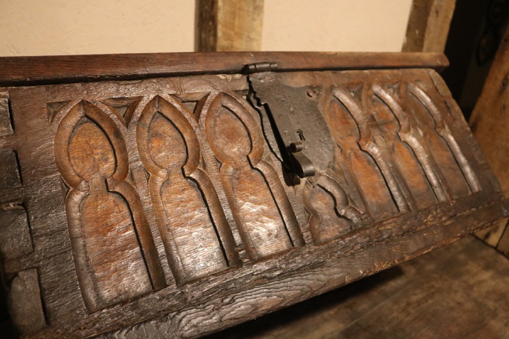 An antique dark brown chestnut wood deed box featuring carved Gothic arch panels and a hand-forged iron lock plate on the front. View XVII