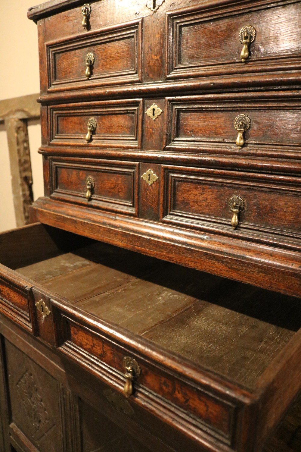 An eighteenth-century dark oak miniature tallboy chest featuring geometric panelled drawer fronts, brass tear-drop handles, and cabriole legs. View V