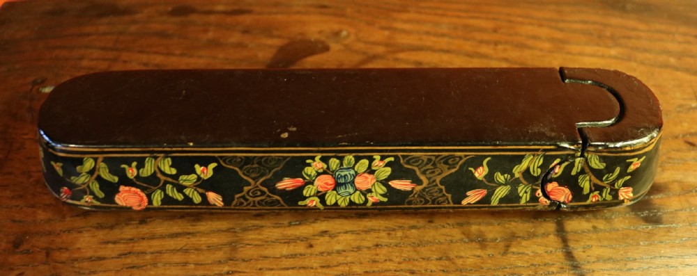 An elongated, rounded antique Indo-Persian lacquered papier-mache pen case featuring hand-painted figures in a landscape with floral end caps. View VI