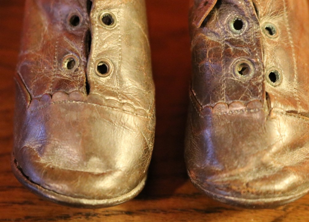 A pair of aged dark brown leather Victorian childrens ankle boots featuring laced fronts with metal eyelets. View V