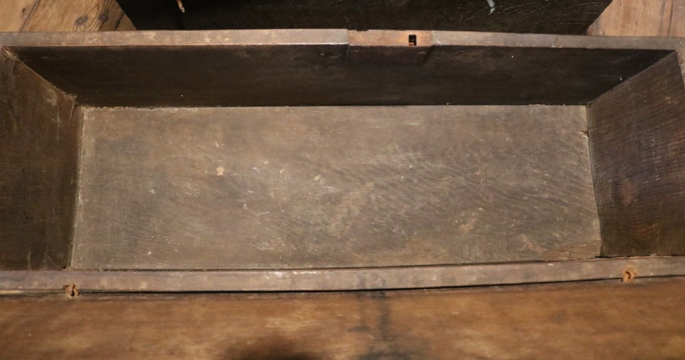A 16th-century Tudor carved oak coffer featuring a carved rosette frieze, central wrought iron lockplate, and slab end supports. View X