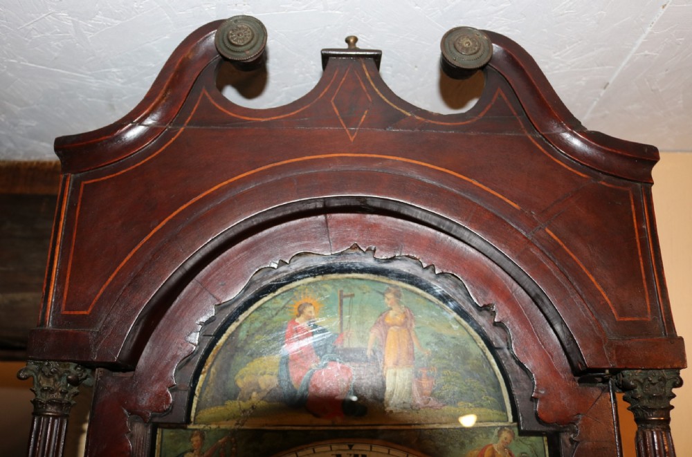 A tall 19th-century Welsh mahogany longcase clock featuring a swan-neck pediment hood, painted arch dial with Roman numerals, and flame mahogany trunk door. View V