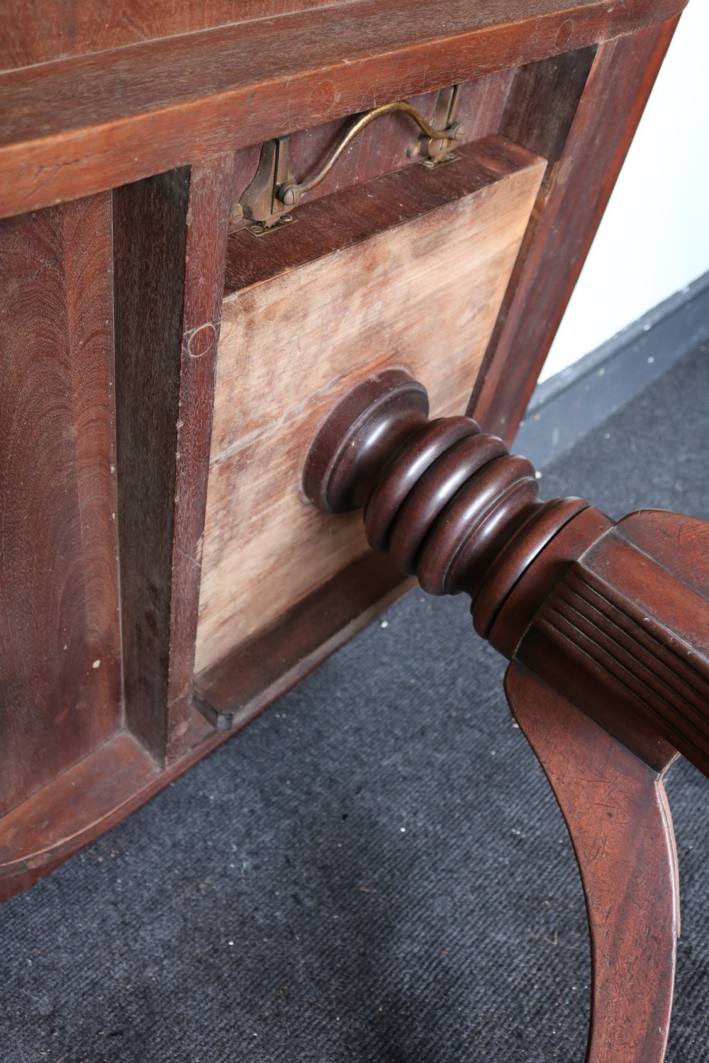 A Regency mahogany breakfast table featuring a rectangular top with reeded edges, a turned central pedestal, and four splayed reeded legs on brass castors. View XV