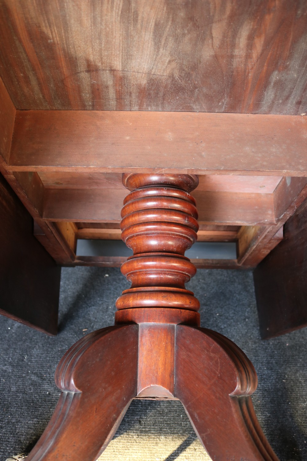 A Regency mahogany dining table featuring a rectangular drop-leaf top supported by a central reeded pedestal and four splayed legs with brass toe castors. View XIII