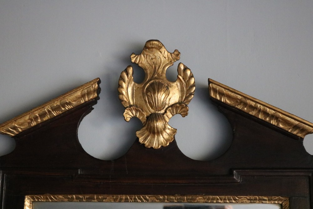 A dark mahogany Georgian Chippendale wall mirror featuring a carved gilt shell cresting, inner gilt moulding slip, and a bottom gilt patera rosette. View II