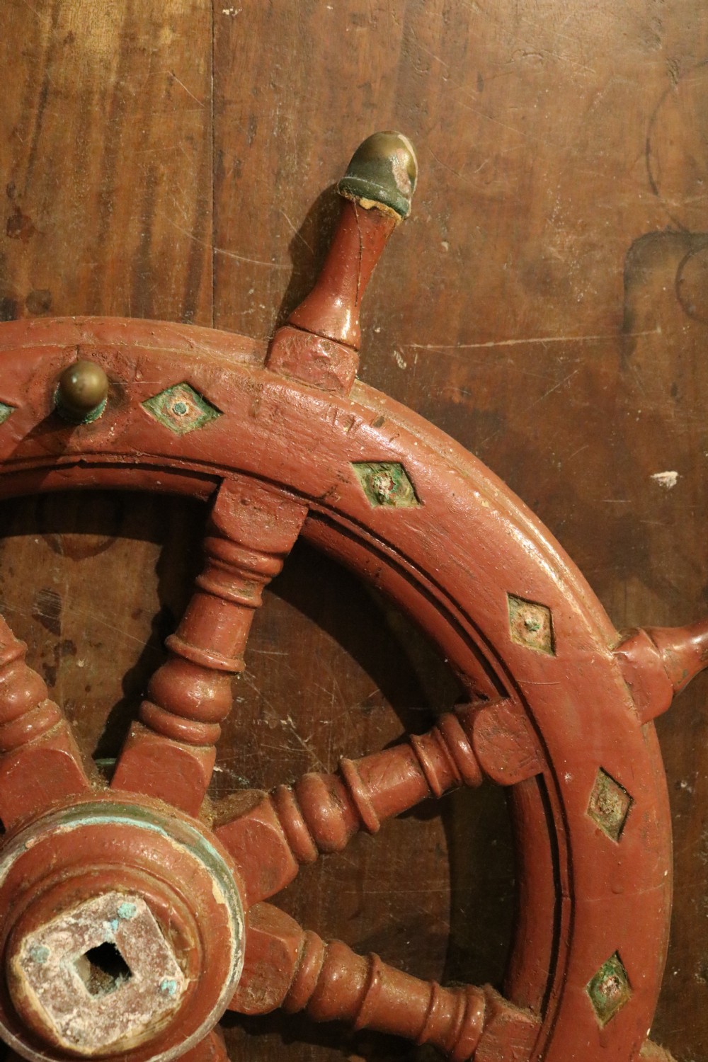 A nineteenth-century Welsh wooden ships wheel finished in deep red paint with turned spokes and green diamond motifs along the outer rim. View II