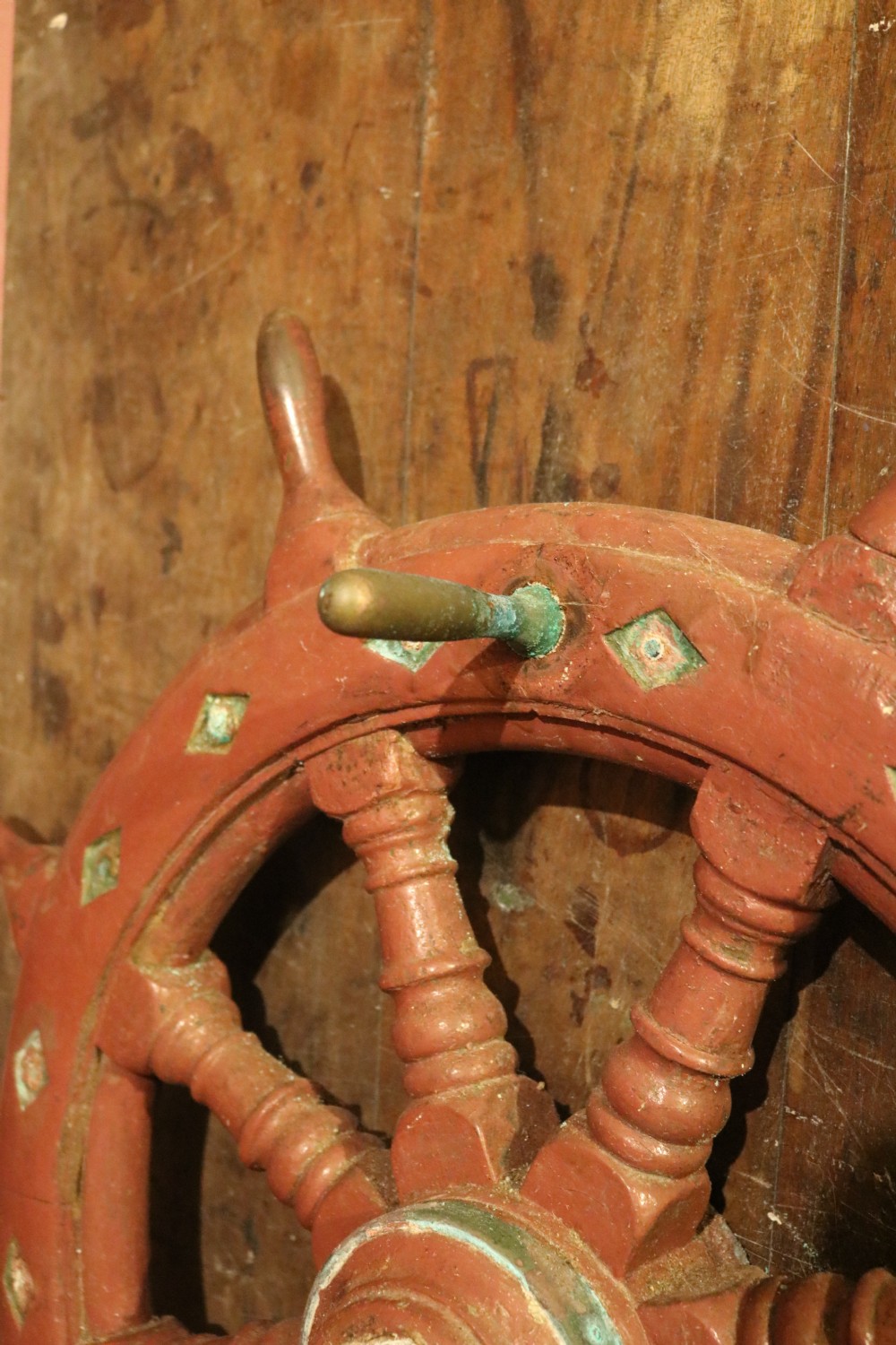 A nineteenth-century Welsh wooden ships wheel finished in deep red paint with turned spokes and green diamond motifs along the outer rim. View III