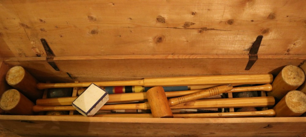 An open pine box containing an antique croquet set with wooden mallets, painted winning posts, and white metal hoops. View III