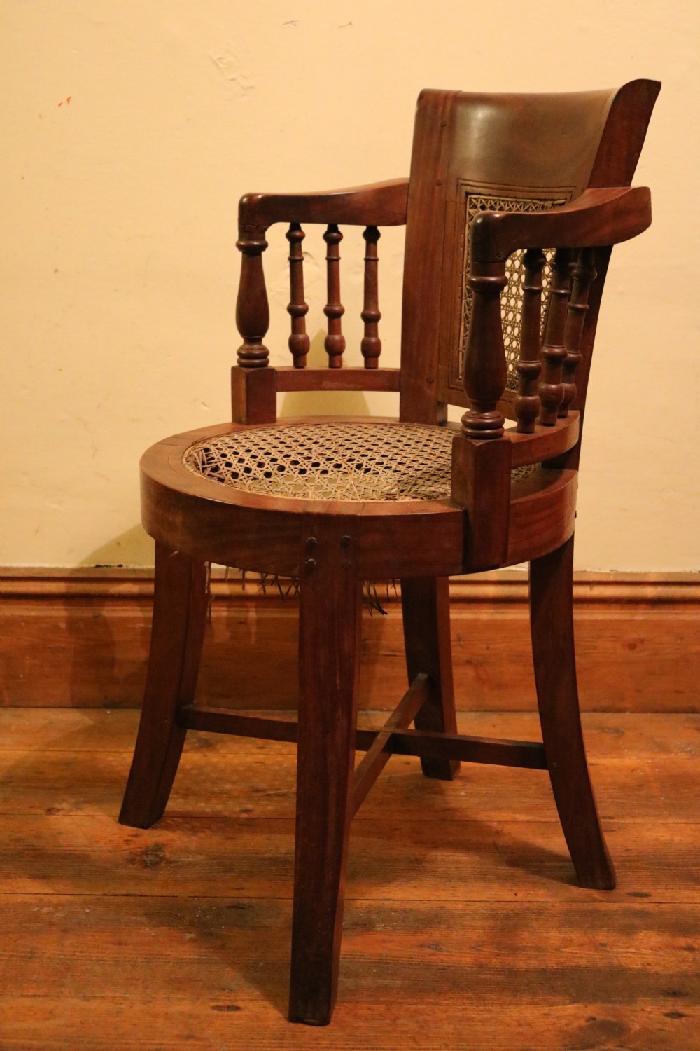 A Victorian mahogany parlour chair featuring a woven cane seat, curved backrest, and turned spindle armrests. View II
