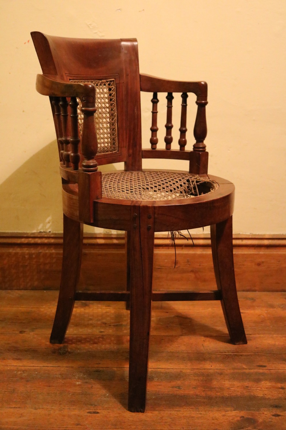 A Victorian mahogany parlour chair featuring a woven cane seat, curved backrest, and turned spindle armrests. View III