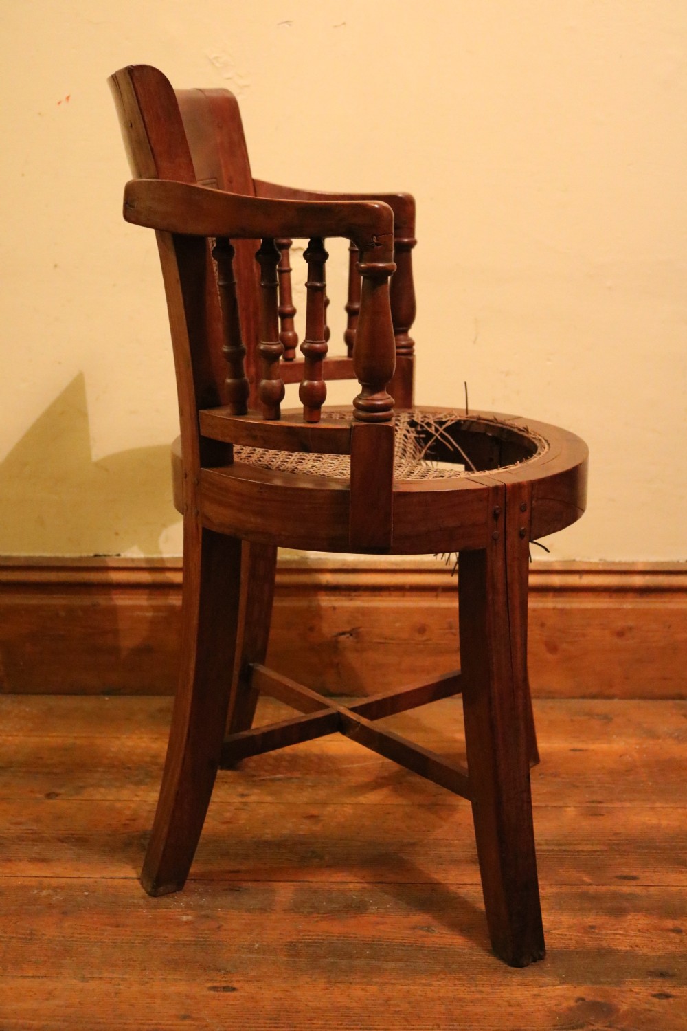 A Victorian mahogany parlour chair featuring a woven cane seat, curved backrest, and turned spindle armrests. View IV