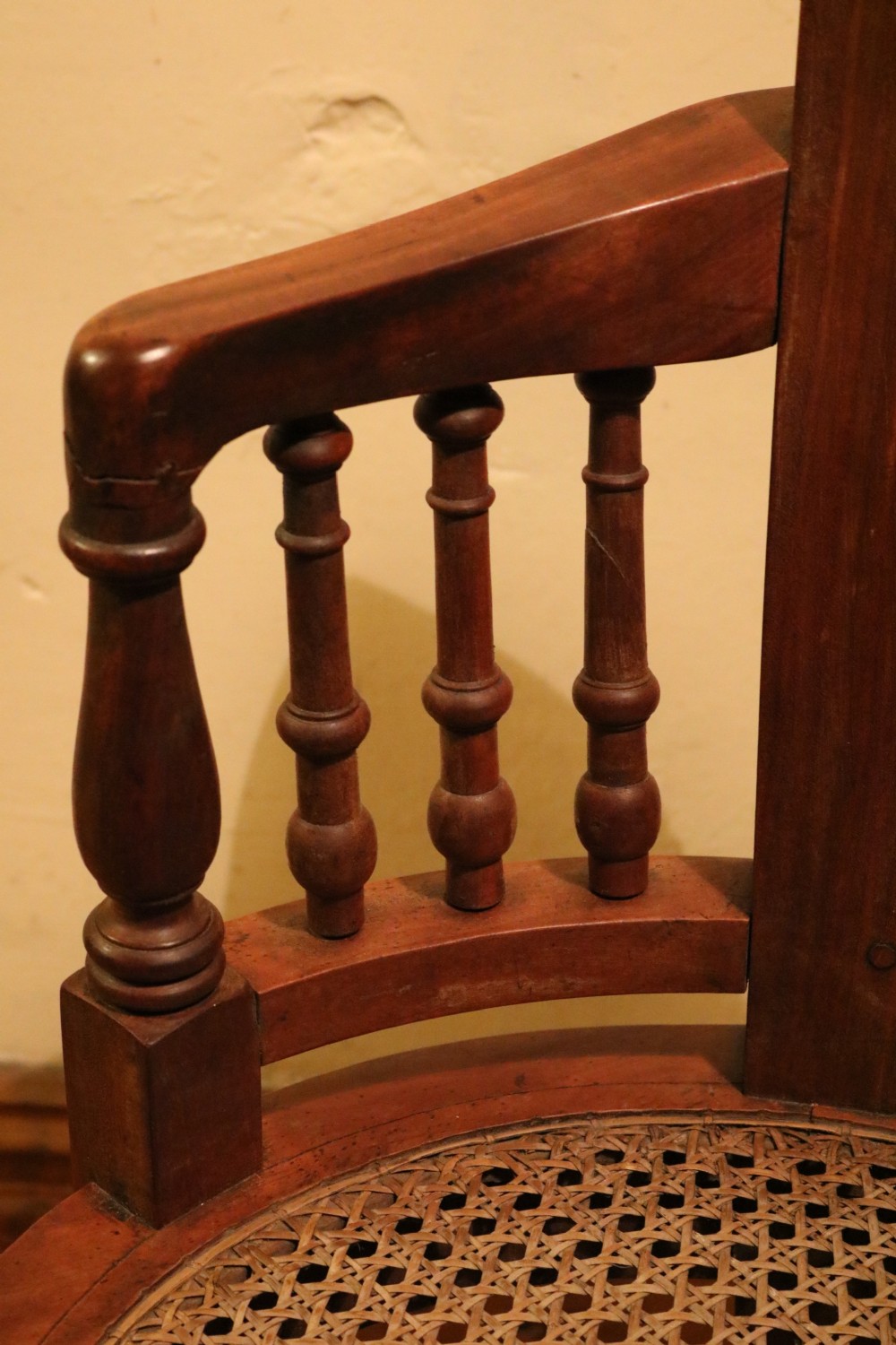 A Victorian mahogany parlour chair featuring a woven cane seat, curved backrest, and turned spindle armrests. View VIII