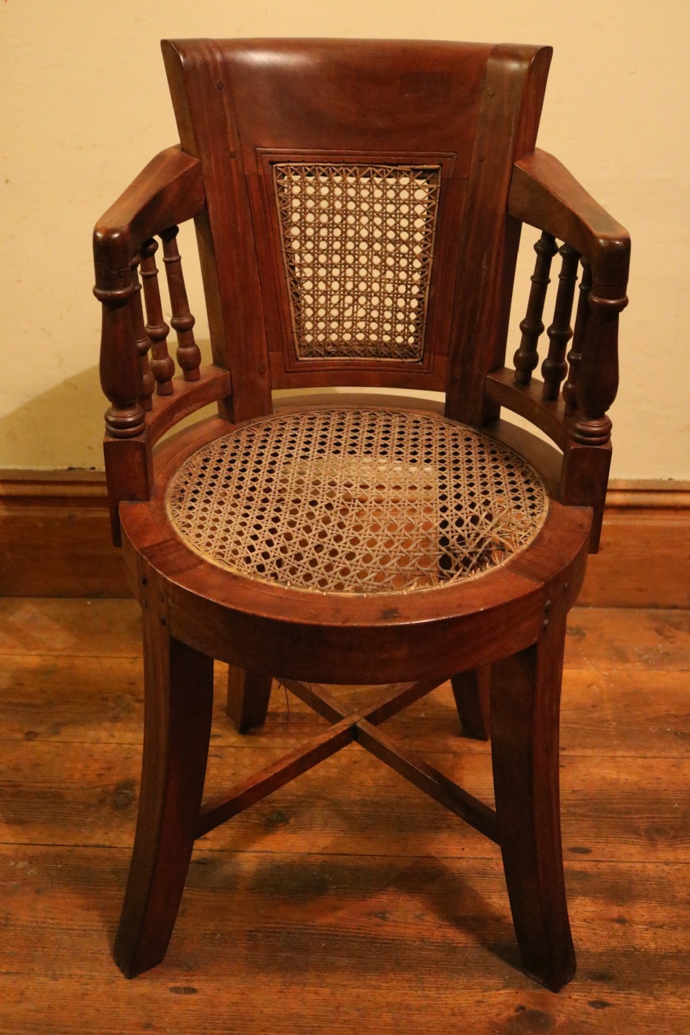 A Victorian mahogany parlour chair featuring a woven cane seat, curved backrest, and turned spindle armrests. View XV