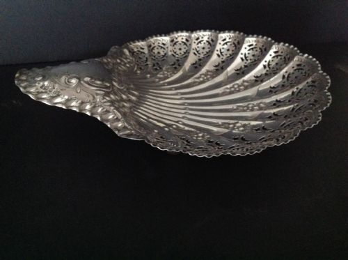 fig 1. A late Victorian silver dish shaped like a scallop shell featuring detailed pierced scrollwork and fluted ridges.