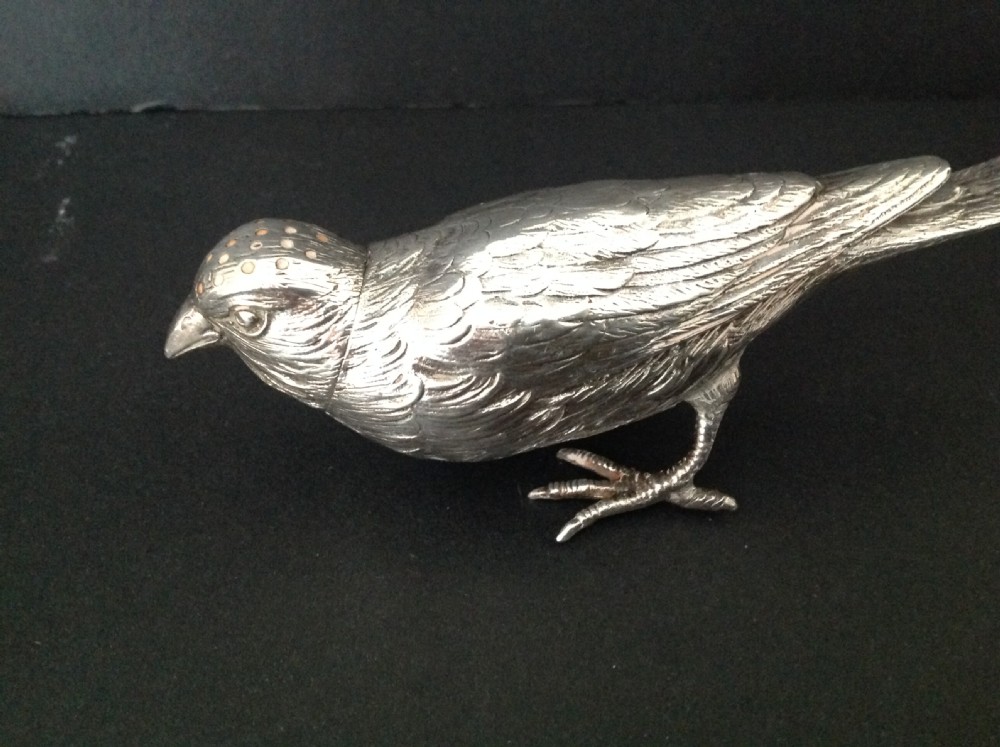 A cast silver pepper pot fashioned in the detailed form of a standing bird with pierced holes on its head.