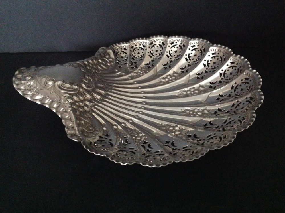 A late Victorian silver dish shaped like a scallop shell featuring detailed pierced scrollwork and fluted ridges.