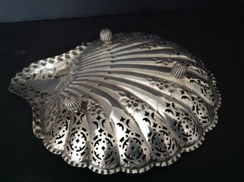 A late Victorian silver dish shaped like a scallop shell featuring detailed pierced scrollwork and fluted ridges. View VI