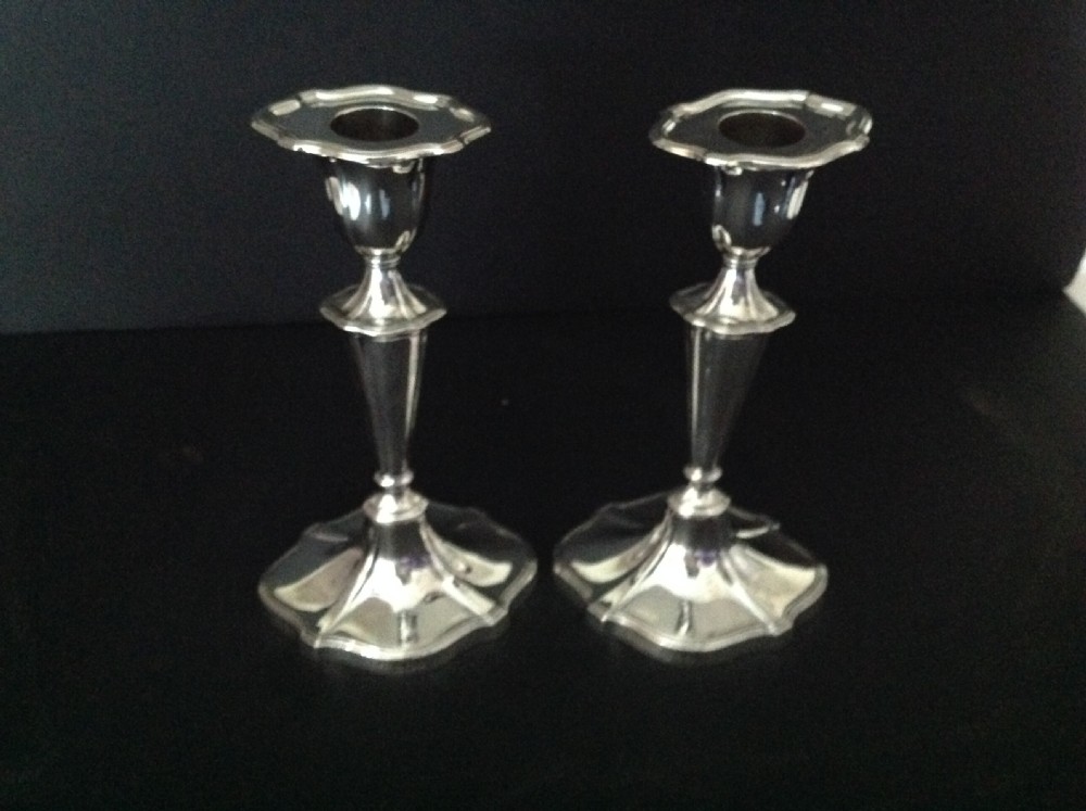 A pair of polished silver Victorian candlesticks featuring shaped scalloped bases, slender tapered stems, and flared capitals.