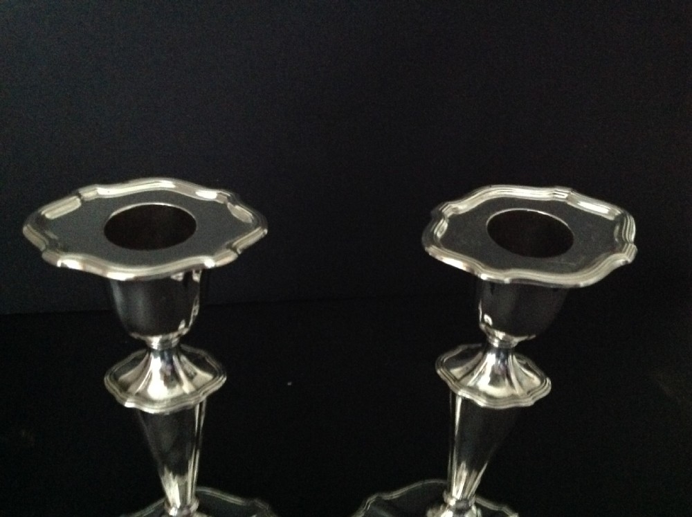A pair of polished silver Victorian candlesticks featuring shaped scalloped bases, slender tapered stems, and flared capitals. View II