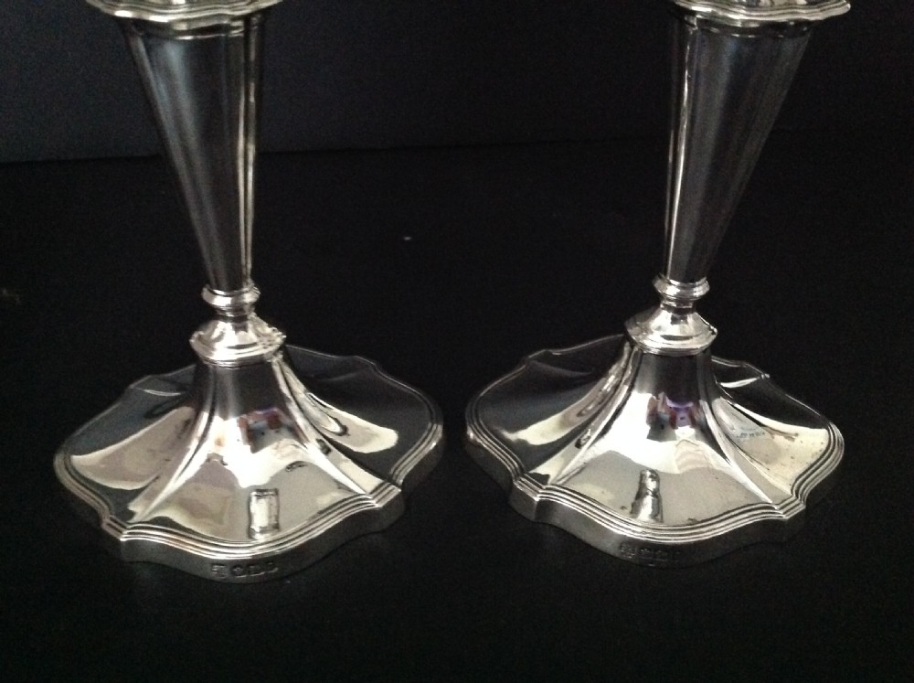 A pair of polished silver Victorian candlesticks featuring shaped scalloped bases, slender tapered stems, and flared capitals. View III