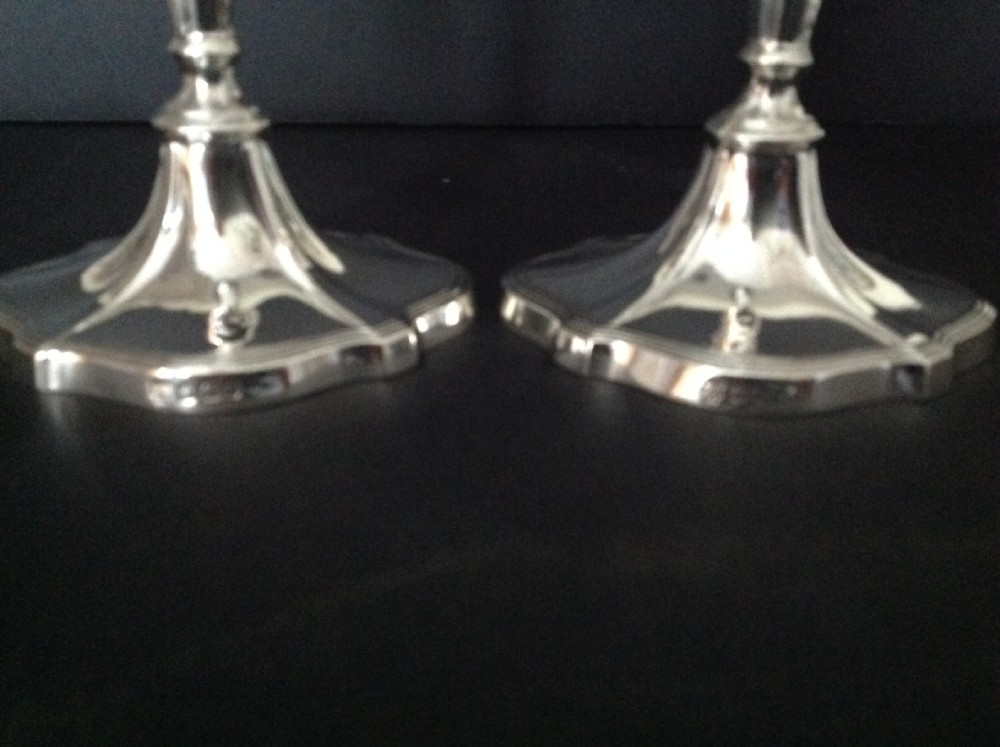 A pair of polished silver Victorian candlesticks featuring shaped scalloped bases, slender tapered stems, and flared capitals. View IV