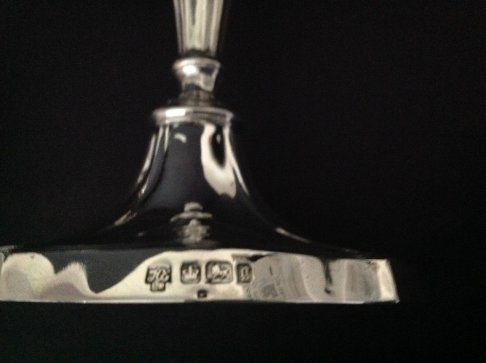 A pair of polished silver Victorian candlesticks featuring shaped scalloped bases, slender tapered stems, and flared capitals. View V