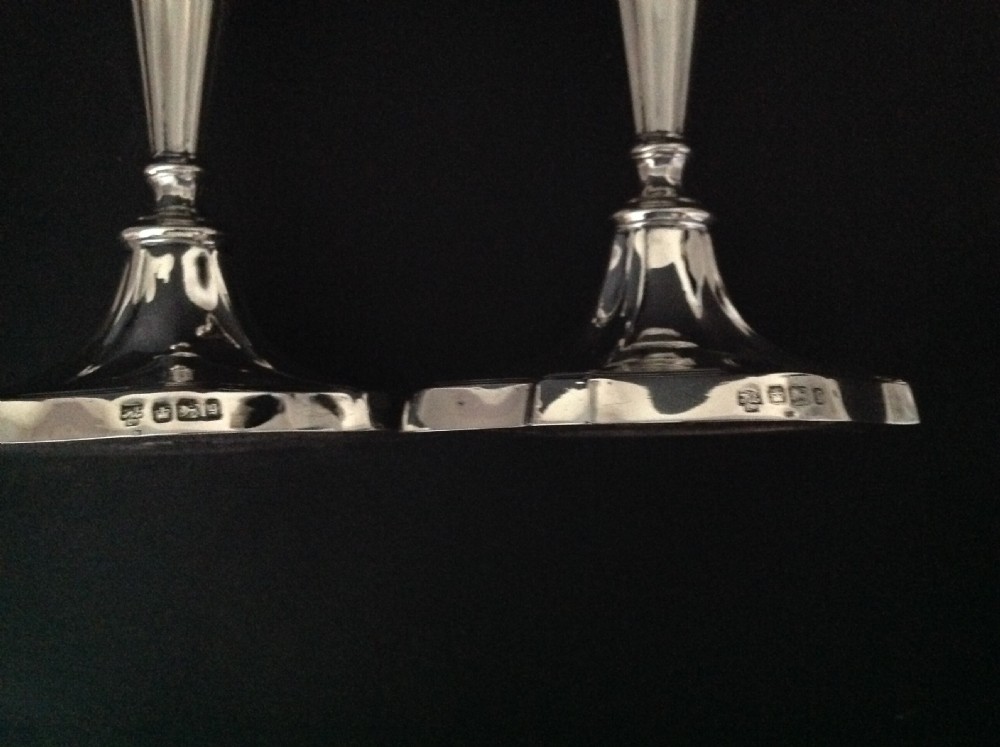 A pair of polished silver Victorian candlesticks featuring shaped scalloped bases, slender tapered stems, and flared capitals. View VI