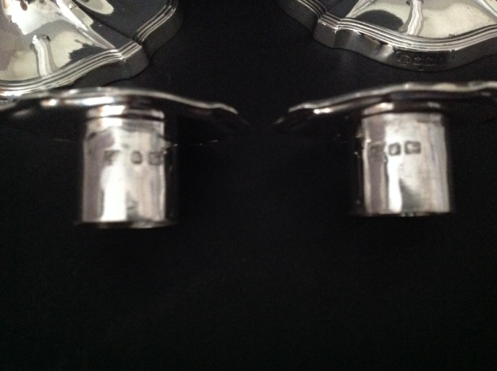 A pair of polished silver Victorian candlesticks featuring shaped scalloped bases, slender tapered stems, and flared capitals. View VII